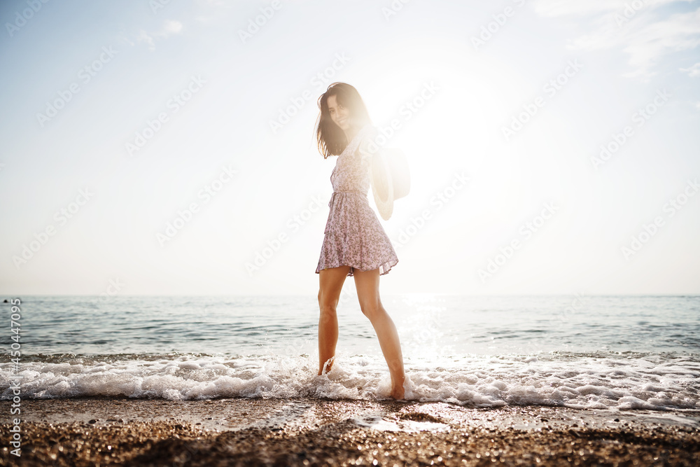 Portrait of young woman walking on the beach on sunrise