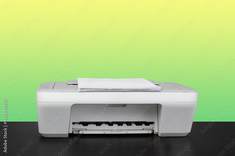 Home laser printer on desk against green background Home laser printer on desk against green background