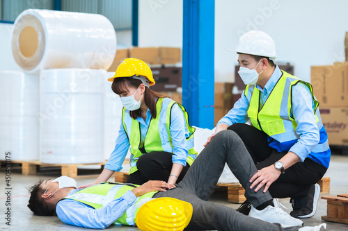The team worker was born in a factory accident. Being assisted by a team of engineers, supervisors or foreman, First aid before being taken to the hospital. Teamwork concept.