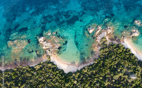 View from above, stunning aerial view of a green coastline with a beautiful beach bathed by a beautiful and turquoise sea. Liscia Ruja, Costa Smeralda, Sardinia, Italy.
