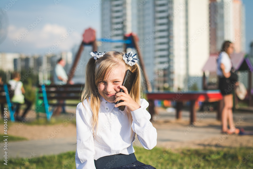 Little girl on the street talking on the phone and writing a message