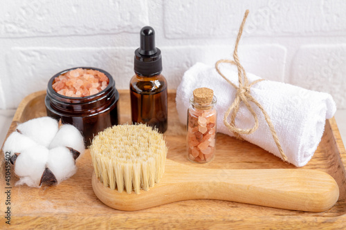 Natural cosmetics set in eco-friendly packaging in wooden tray with ctton flower and towel. SPA  bath beauty products.