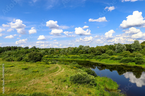 Sesupe River  Kaliningrad Region. Cumulus clouds are reflected in the river water. Green meadows in summer