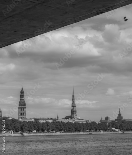 Black and white view from under the bridge to the panorama of Riga and a small hanging chair.