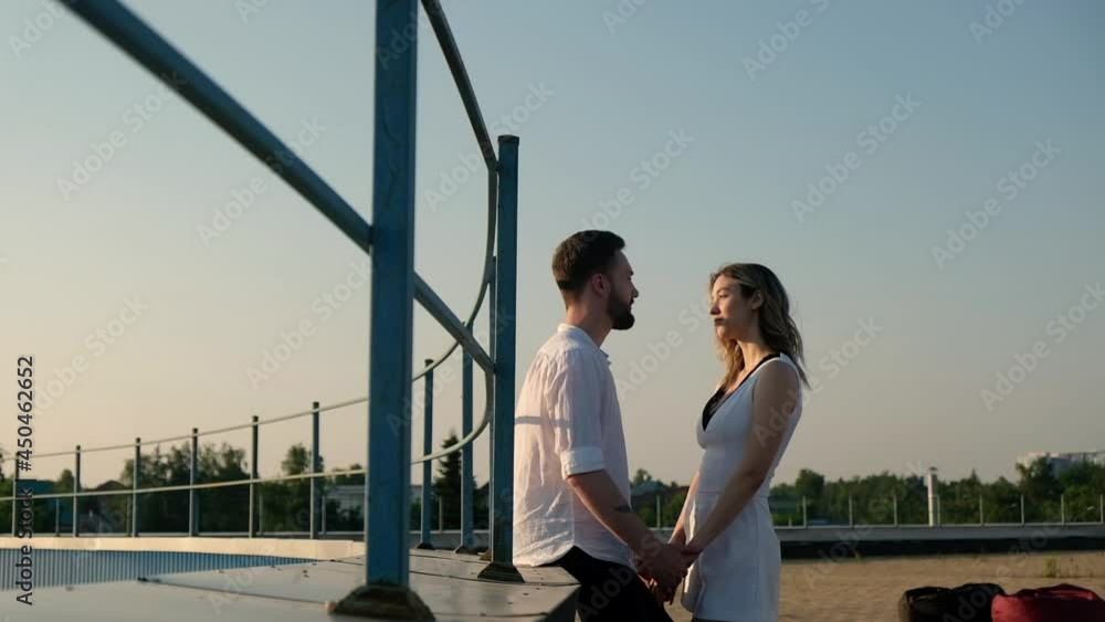 Young Caucasian lovers, woman and man are standing on roof and hugging. guy in love holds girl's hand. couple of people on roof at sunset in summer enjoying together Young Caucasian lovers, woman and man are standing on roof and hugging. guy in love holds girl's hand. couple of people on roof at sunset in summer enjoying together