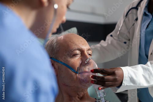 Obraz na plátně Side view of senior patient breathing assisted by respiratory tube in hospital intesive care
