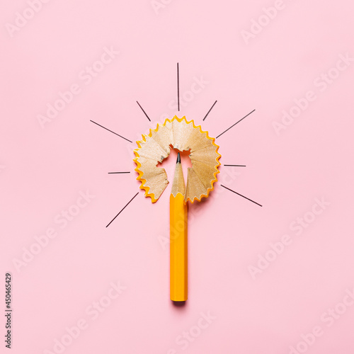 Graphite pencil with a pen waste that is shaped like a compass or the Sun on pastel pink background. Creative ideas and back to school concept. Flat lay, top view.