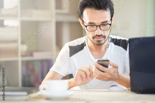 young man using mobile at workplace during stay at home, freelance,work from home and learning online concept
