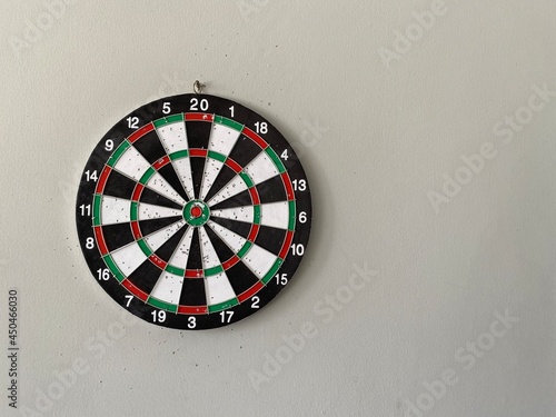 The arrow board which is dominated by black, white, green and red colors is attached to the wall. Focus on the red dot in the center and reach the target that has been prepared