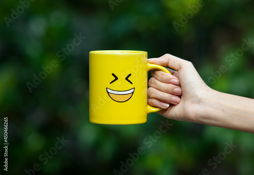 Hand holding yellow glass with smiley emoticon