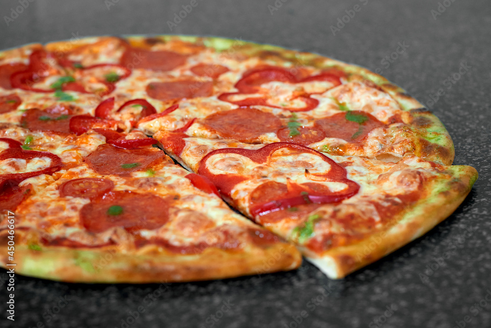 Delicious pizza with salami, red pepper and tomatoes