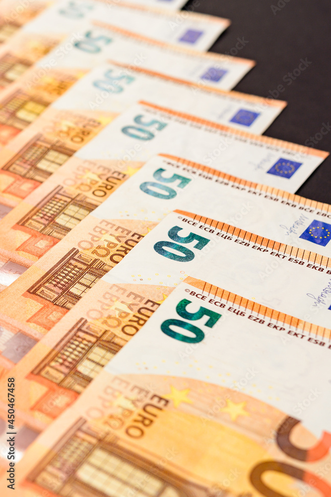 Diagonal line of euro notes isolated on black background, salary in euros.