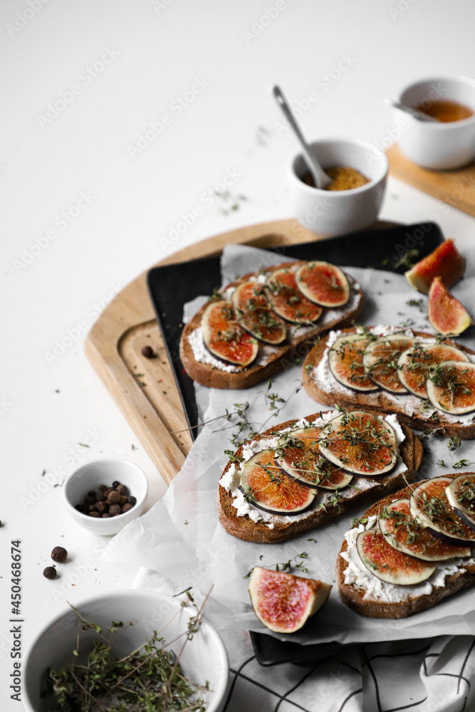 toast with figs, cream cheese and thyme on a black plate, ingredients on the breakfast table, healthy vegetarian snack or dish, white background, close up, flat lay with copy space toast with figs, cream cheese and thyme on a black plate, ingredients on the breakfast table, healthy vegetarian snack or dish, white background, close up, flat lay with copy space