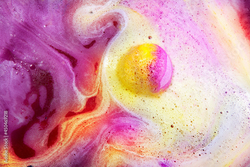 Dissolving color bath bomb in water, closeup.