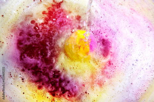 Dissolving color bath bomb in water, closeup.