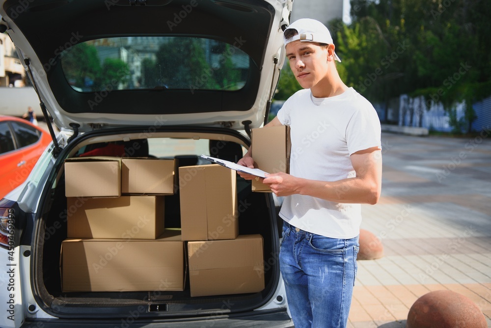 Smiling delivery man standing in front of his car Smiling delivery man standing in front of his car