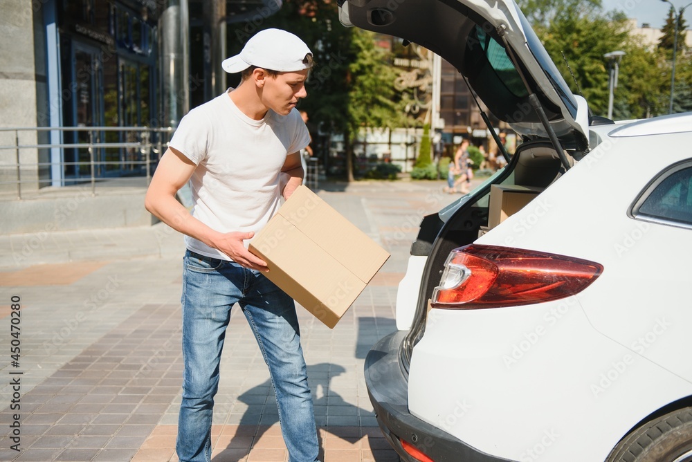 Smiling delivery man standing in front of his car Smiling delivery man standing in front of his car