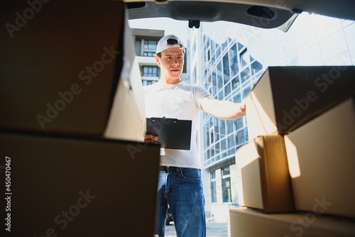 Delivery man picking up box from car.