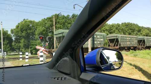 Fotografie Vehicle Stopped In Front Of Railway Semaphore With Train At Railroad Crossing
