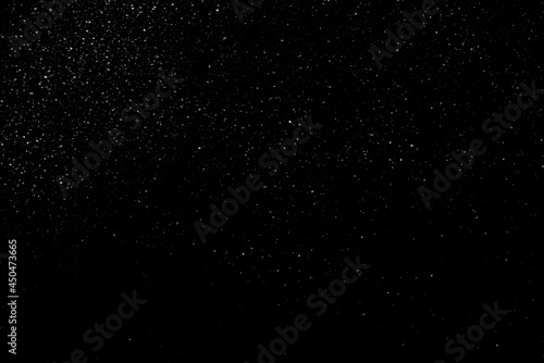 Falling snow on a black background. small particles with bright dots starry sky. Сhaotic white bokeh. light spots texture. abstract.