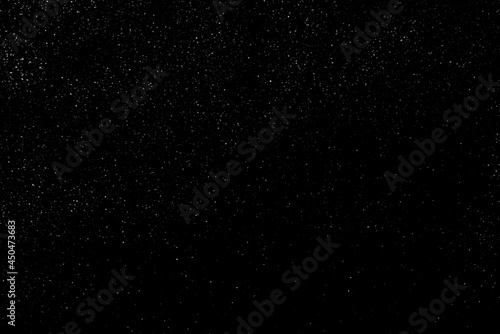 Falling snow on a black background. small particles with bright dots starry sky.   haotic white bokeh. light spots texture. abstract.
