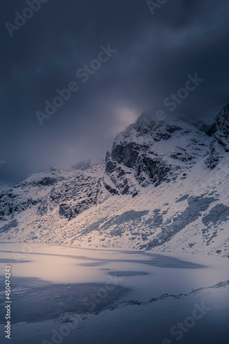 Dramatic cloudscape over Kościelec Peak, High Tatra Mountains, Poland. Czarny Staw Gąsienicowy in the valley. Selective focus on the rocks, blurred background.