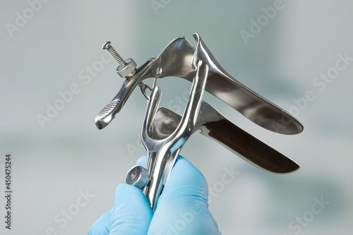 close-up of doctor's hand in medical gloves holding a speculum
