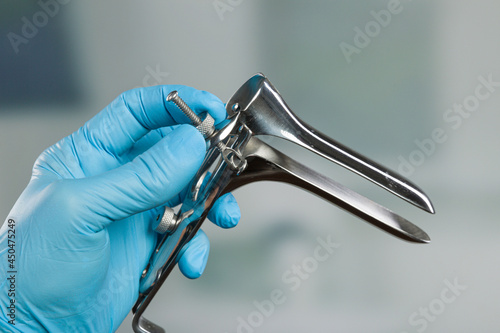 close-up of doctor's hand in medical gloves adjusting a speculum
