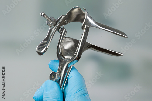 close-up of doctor's hand in medical gloves holding a speculum