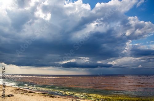 Big rain clouds over wild sandy coast reflected in a small shallow of the Baltic Sea in Vecaki, Latvia © Tanya Keisha