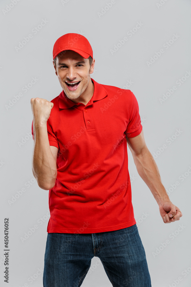 Young delivery man wearing uniform screaming while making winner gesture Young delivery man wearing uniform screaming while making winner gesture