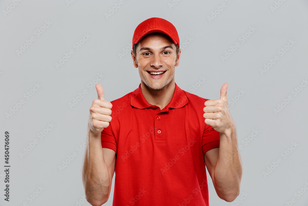 Young delivery man wearing uniform smiling while gesturing thumbs up Young delivery man wearing uniform smiling while gesturing thumbs up