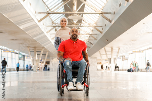 Muslim woman and disabled man looking at camera at train station © Drobot Dean