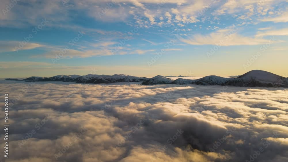 Aerial view of vibrant sunrise over white dense fog with distant dark peaks of Carpathian mountains on horizon. Aerial view of vibrant sunrise over white dense fog with distant dark peaks of Carpathian mountains on horizon.