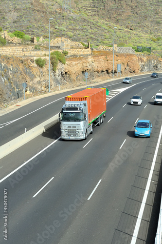 Truck transporting a shipping container among highway traffic.