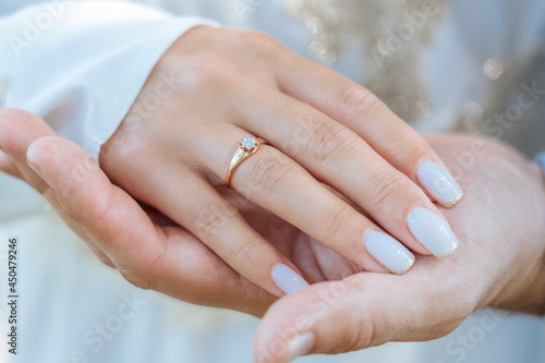 A woman s palm with a gold ring on her finger lies in a man s palm