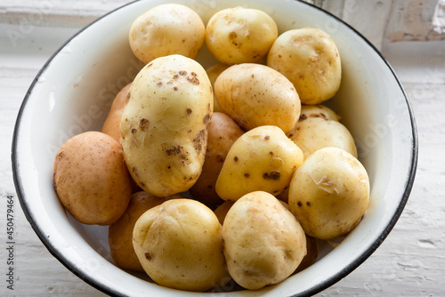 Fresh raw washed organic potatoes in bowl at window sill