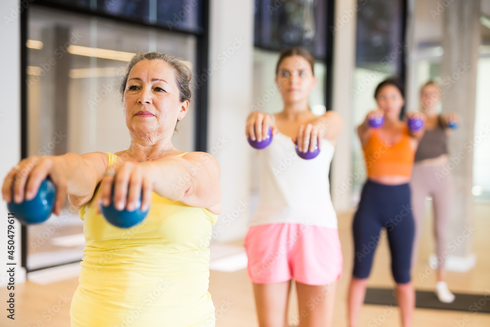 Fototapeta premium Positive women practicing pilates with balls at group class in yoga studio