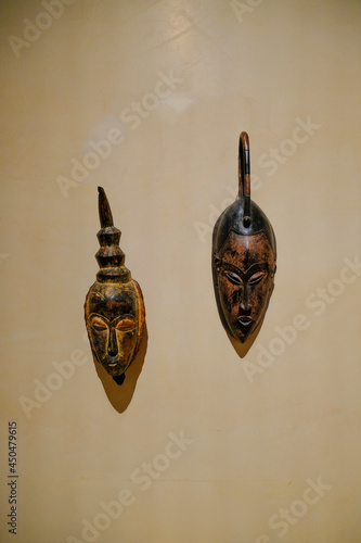  Two wooden African masks on white wall close-up in the museum of Magnani Rocca, Parma, Italy. African culture photo