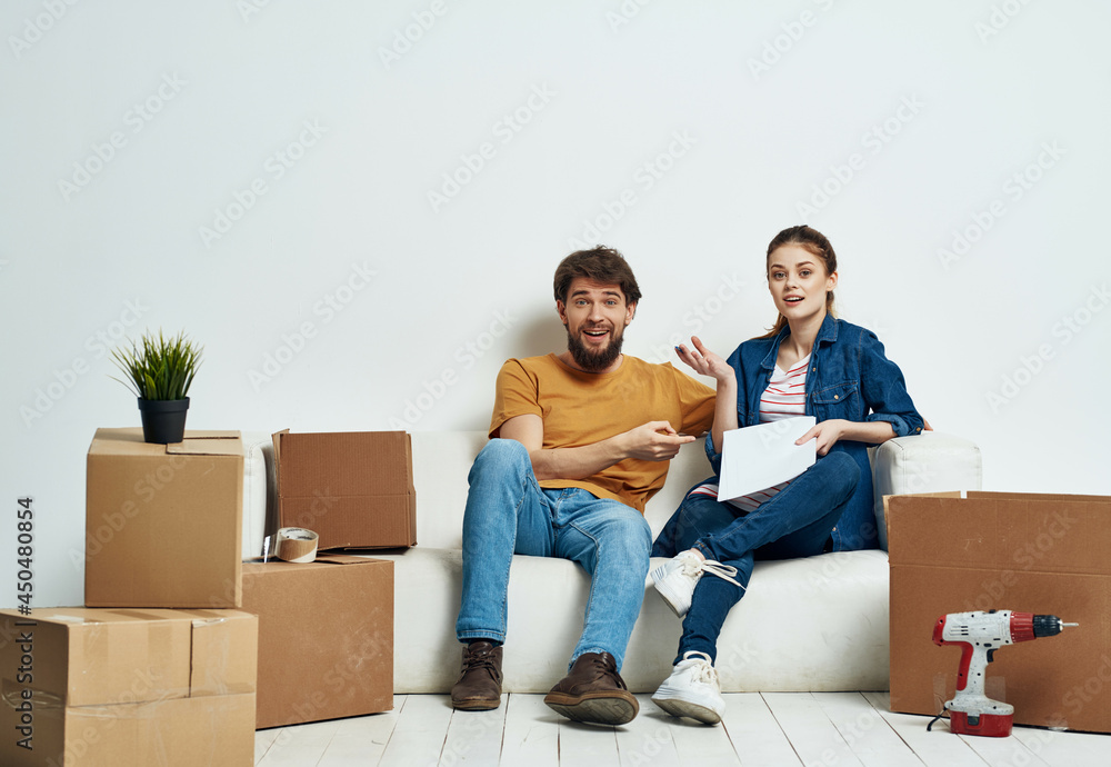 Young family i am sitting on the couch boxes with repair things unpacking Young family i am sitting on the couch boxes with repair things unpacking