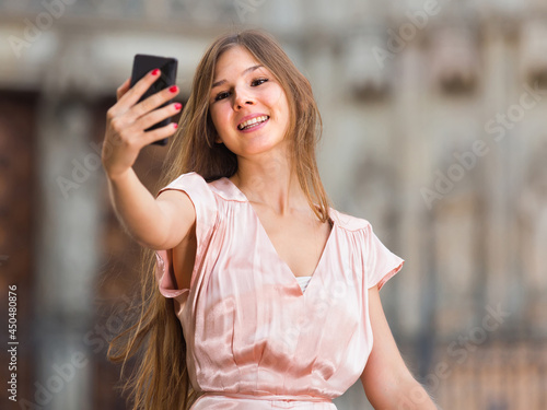 Smiling american female standing in the street and taking selfie