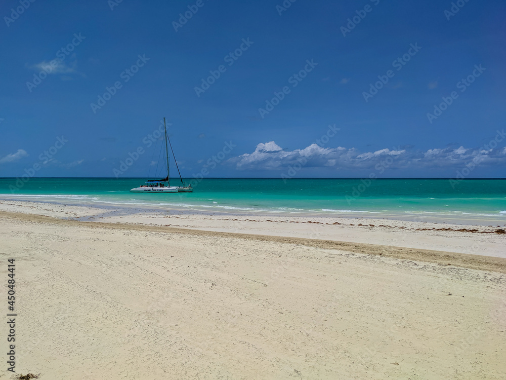 Cayo Guillermo, Cuba, 16 may 2021: Nice view of Pilar beach with white sand and azure ocean against the blue sky. The catamaran with tourists stopped near the shore for swimming and snorkeling. Cayo Guillermo, Cuba, 16 may 2021: Nice view of Pilar beach with white sand and azure ocean against the blue sky. The catamaran with tourists stopped near the shore for swimming and snorkeling.