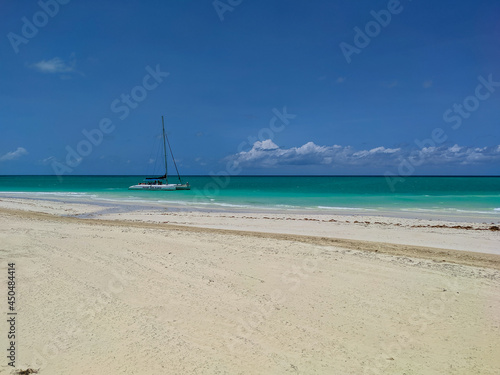 Cayo Guillermo, Cuba, 16 may 2021: Nice view of Pilar beach with white sand and azure ocean against the blue sky. The catamaran with tourists stopped near the shore for swimming and snorkeling.