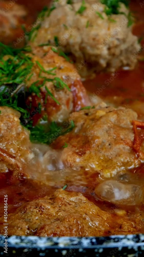 Cooking delicious meatballs in creamy tomato sauce in frying pan. Small round cutlets filled with spicy sauce are stewed in skillet. Domestic kitchen. Vertical video. Cooking delicious meatballs in creamy tomato sauce in frying pan. Small round cutlets filled with spicy sauce are stewed in skillet. Domestic kitchen. Vertical video.