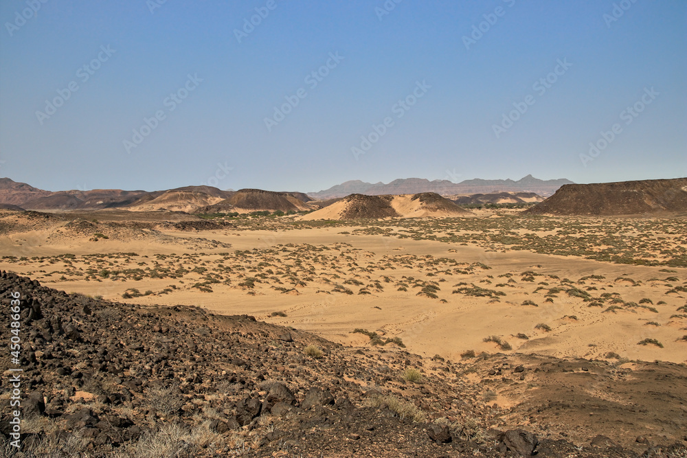 sand dunes with grass in front of distant mountain range, stunning african landscape, savanna	
