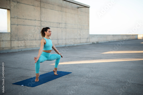 Young woman practising yoga outdoors. Beautiful young girl doing yoga fitness exercise.