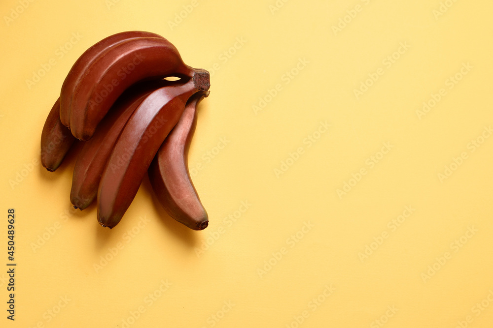 Obraz premium Tasty red baby bananas on yellow background, top view. Space for text