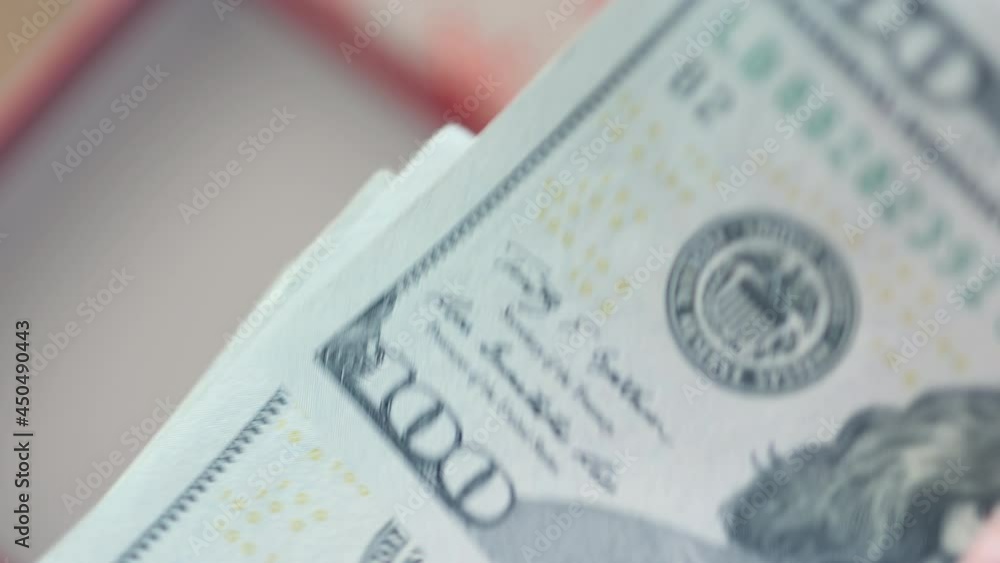 red Christmas gift present box in background and hand counting money hundred dollars banknotes American dollars in a foreground close-up view. winter holidays costs expenses concept red Christmas gift present box in background and hand counting money hundred dollars banknotes American dollars in a foreground close-up view. winter holidays costs expenses concept