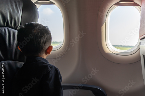 Bilde på lerret Little boy looking out of window in airplane, lonely and homesick concept, low k