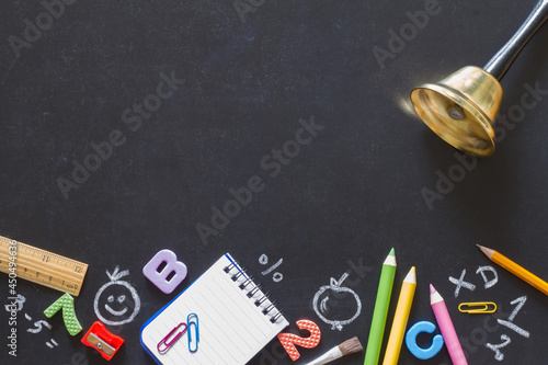 Bell and school supplies on blackboard, back to school concept photo